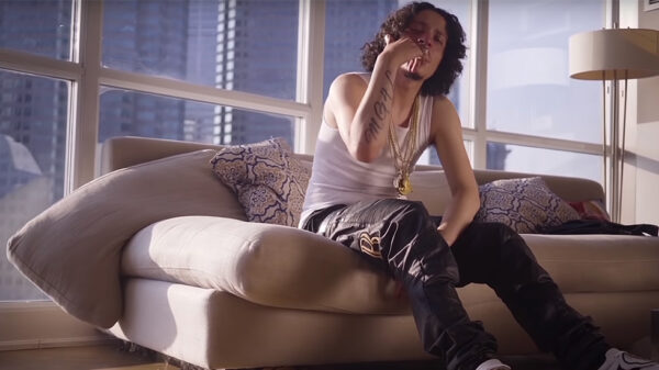 Casper TNG and Jmak release Number 3 video in advance of No Cosign album. In this screenshot from the video, Casper can be seen sitting on a couch in a nice condo, wearing a hat.