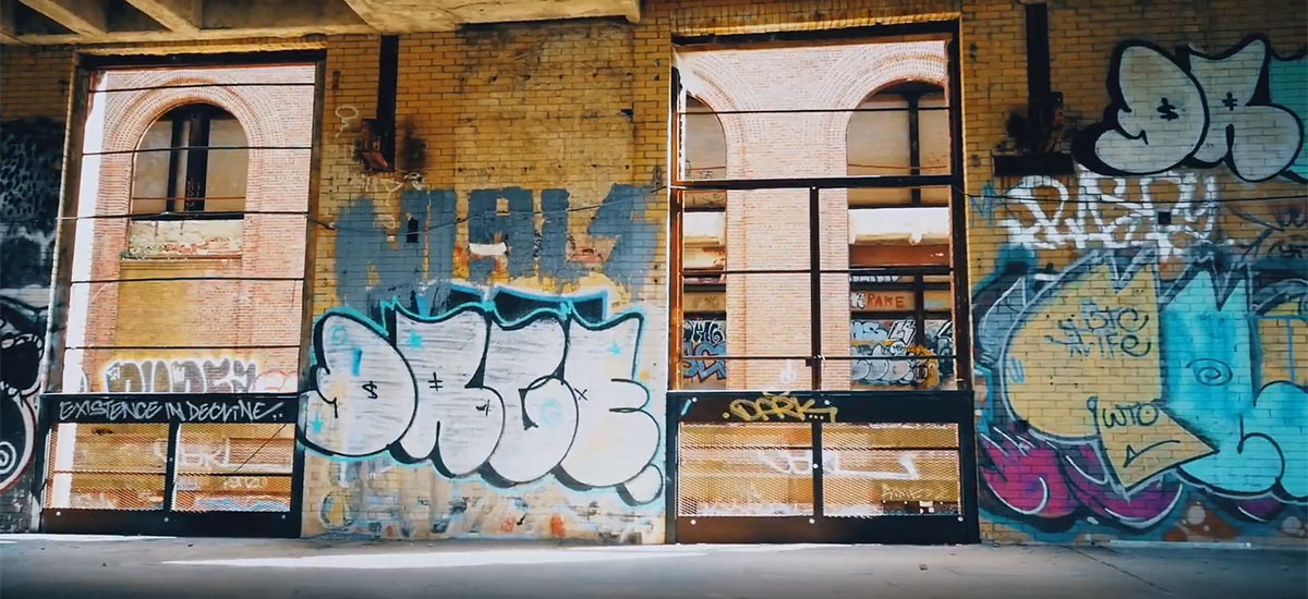 A scene from the Mala Reignz video Greener Side which shows an empty warehouse with graffiti on the wall.