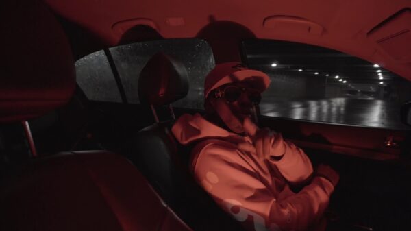 Dyces Trench sits in a car in a scene from the Flashing Lights music video.