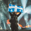 Rapper Jazz Cartier holds up a Quebec flag during his performance on Day 1 of FEQ 2019