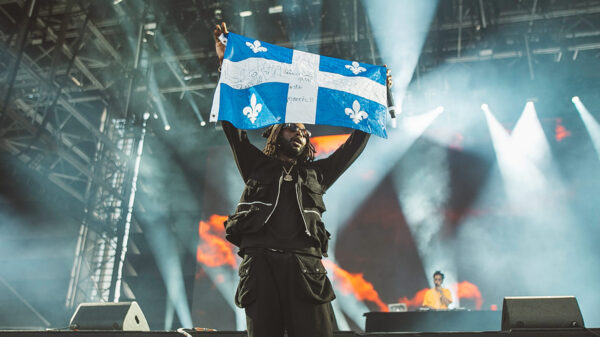 Rapper Jazz Cartier holds up a Quebec flag during his performance on Day 1 of FEQ 2019