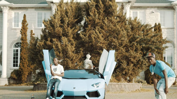 A scene from the new Burna Bandz video for CROS. Burna can be seen rapping his verse next to a luxury car.