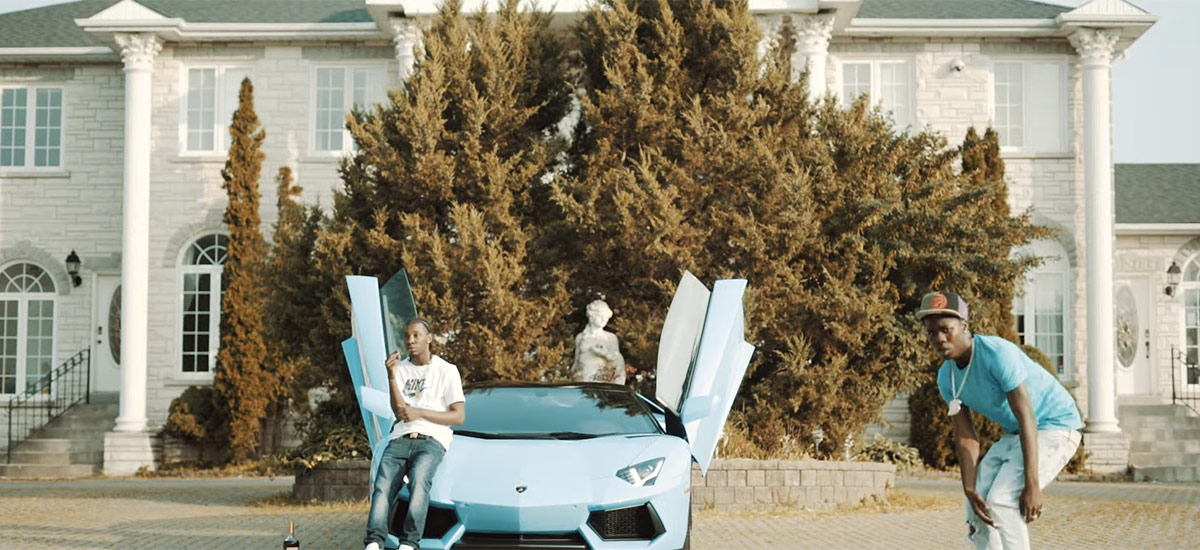 A scene from the new Burna Bandz video for CROS. Burna can be seen rapping his verse next to a luxury car.