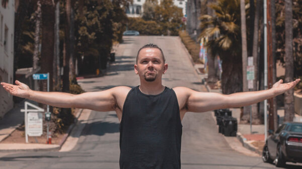 Photo of Nova Scotia-based recording artist EPDMC, standing in the middle of a street with his arms spread.