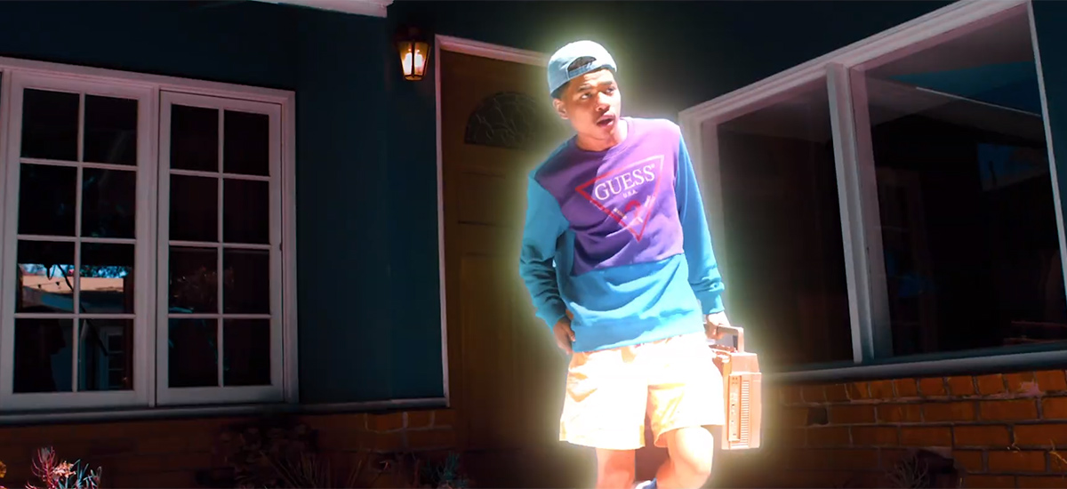 Budding star Bblasian in his new video for Upper Hand. He is wearing a purple and blue shirt, a backwards blue hat, and holding a boombox.