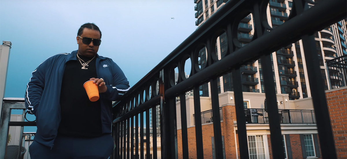 Toronto rapper Vanauley Stacks leans against a railing on a Toronto rooftop in a scene from his new music video for Idiots.