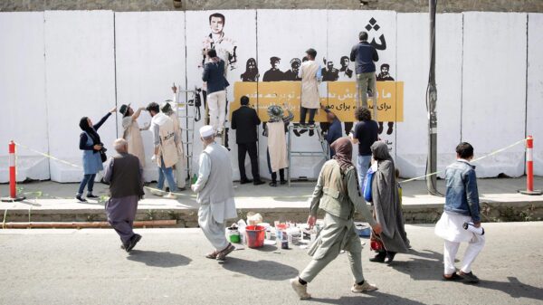 Residents in Kabul, Afghanistan walk past artists from the ArtLords organization as they paint a mural of journalists who were killed in 2018. (AP Photo/Massoud Hossaini)