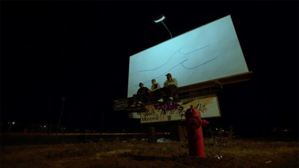 The Planet Giza trio sit on a roadside billboard advertisement