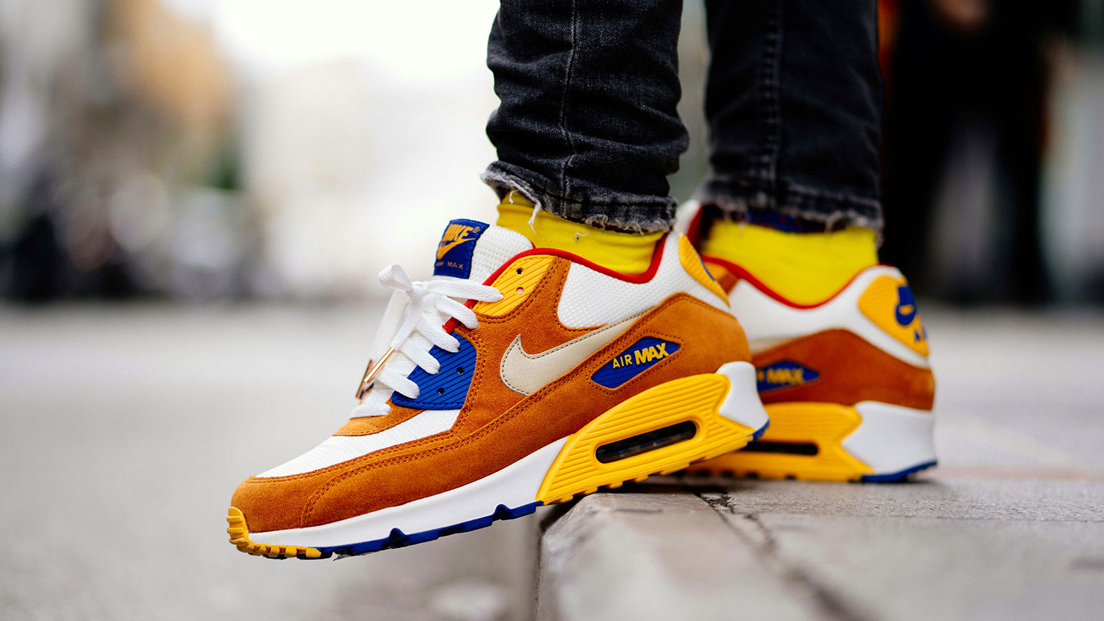 Colorful Nike sneakers worn on a city street curb.
