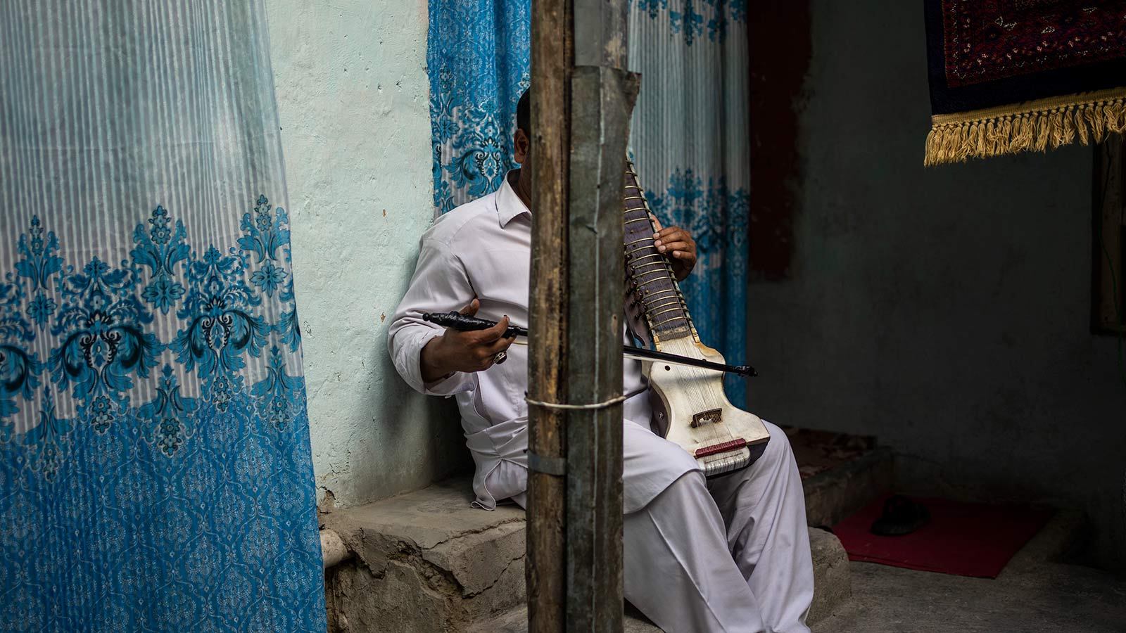 An Afghan musician poses for a portrait with his dilruba in Kabul, Afghanistan