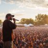 A superstar rapper performs at a festival to a very large crowd.