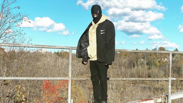 Canadian rapper Sayzee standing by train tracks
