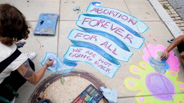 An abortion-rights activist writes the words Abortion Forever For All in chalk