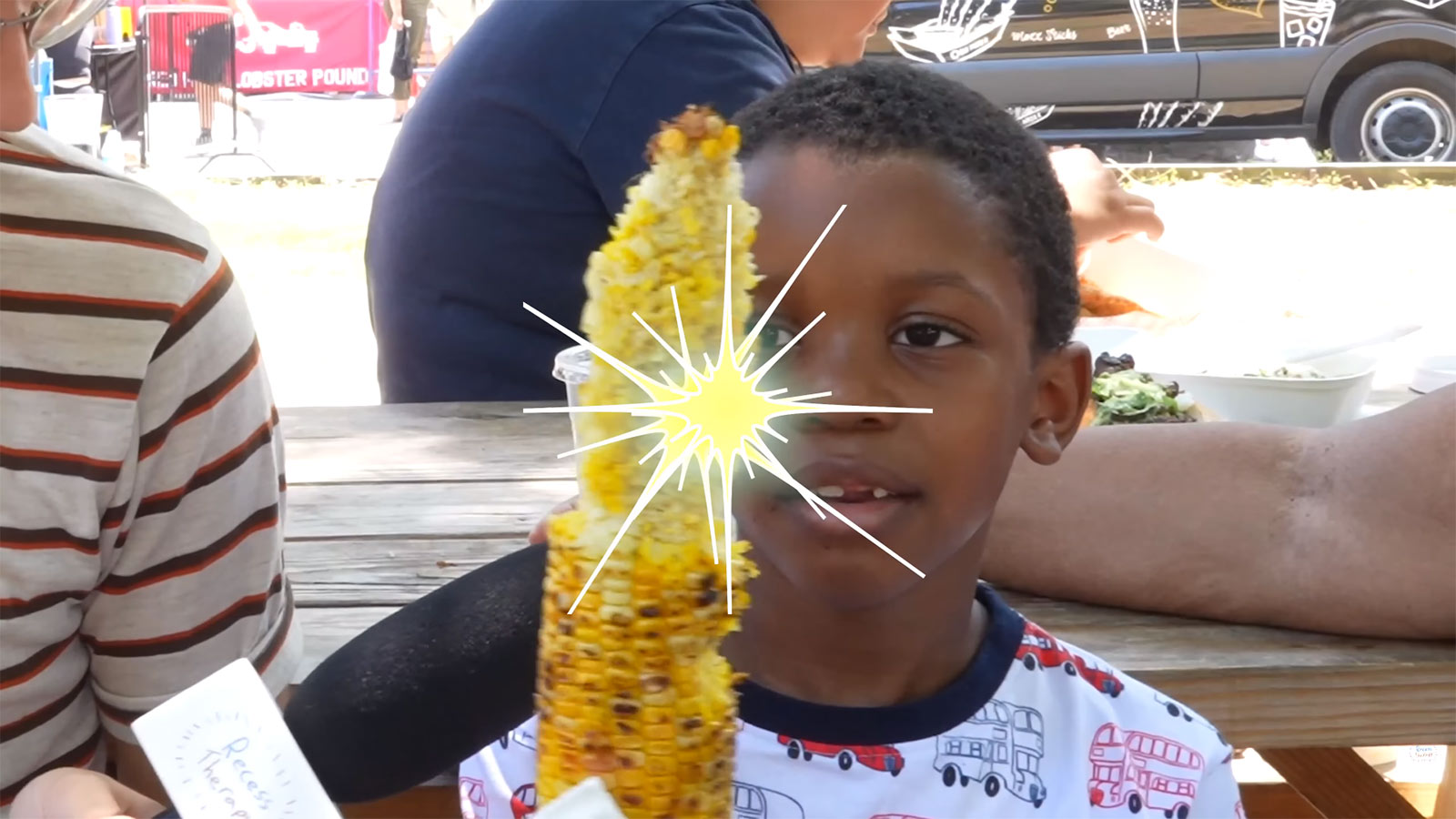 Corn Kid looks at an ear of corn with deep adoration