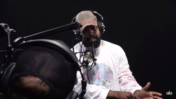Rapper Kanye West wearing a white shirt, brown hat, headphones and sitting in front of a microphone during a recent interview