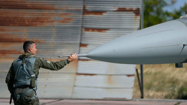 An adult male touches the front end of a fighter jet