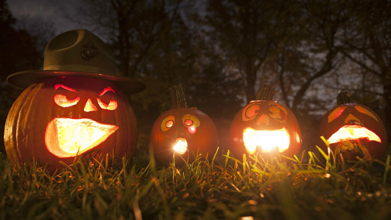 Four carved halloween pumpkins with lit candles