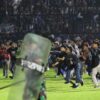 Fans and riot police running onto a soccer field in Indonesia
