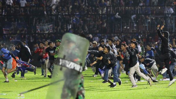 Fans and riot police running onto a soccer field in Indonesia
