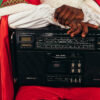 A man in a Santa costume holds a boombox on his lap.