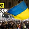 A large crowd is seen under a massive Ukrainian flag