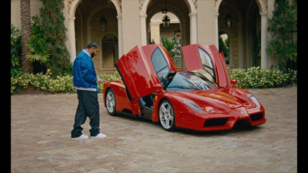 Drake stands next to a red Ferrari