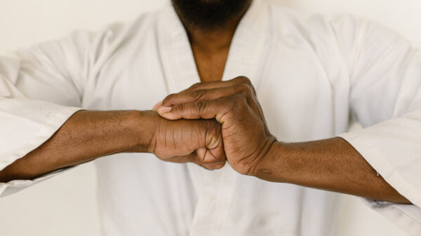A man wearing a Karategi holds his clenched fist into his palm
