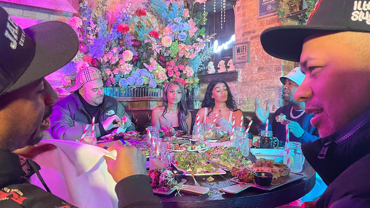 Several people sitting around a table at a restaurant including rappers Peter Jackson and Tony Yayo.