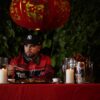 Rapper Quake Matthews holds chopsticks while eating a plate of General Tao chicken