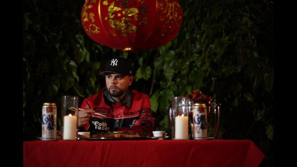 Rapper Quake Matthews holds chopsticks while eating a plate of General Tao chicken