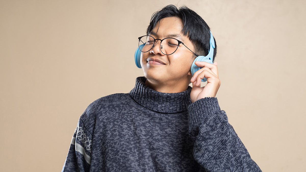A young man wearing glasses listening to headphones