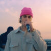 Justin Bieber in a pink toque holding a microphone