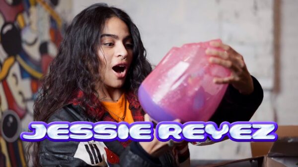 A woman holding a toy and the words 'Jessie Reyez' at the bottom of the image.