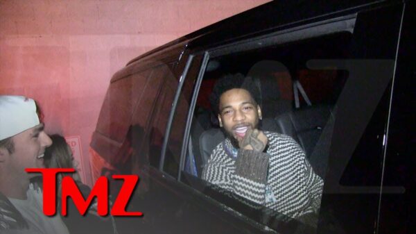 A rapper sitting in the back of a car is approached by a happy fan