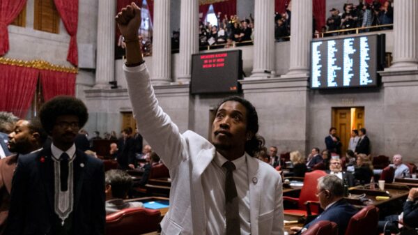 A man in a white suit raises a fist in a government building.