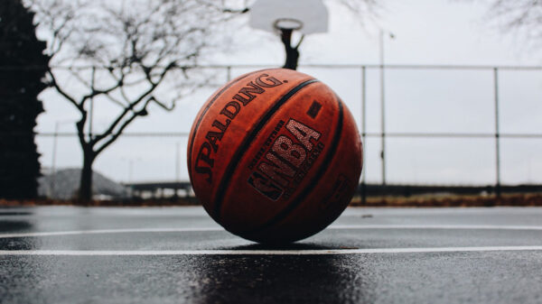 A basketball sits unattended on an outdoor basketball court.
