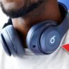 A red arrow points at a pair of the new Beats by Dre headphones around a man's neck