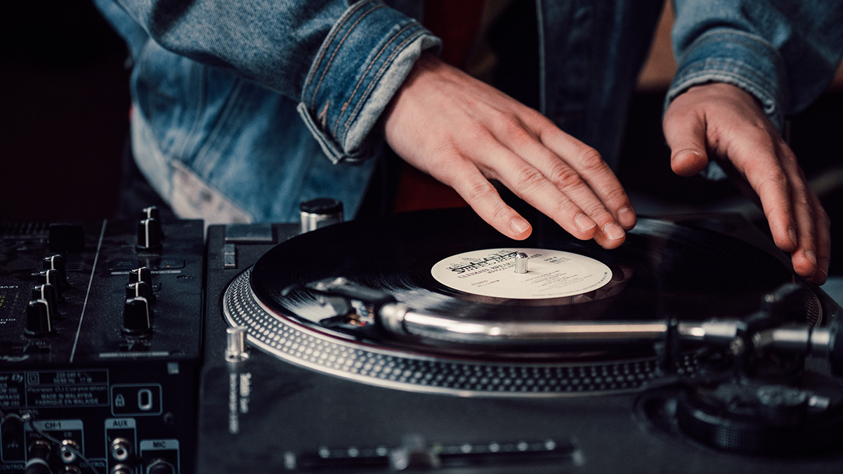A DJ scratching a vinyl record on a turntable