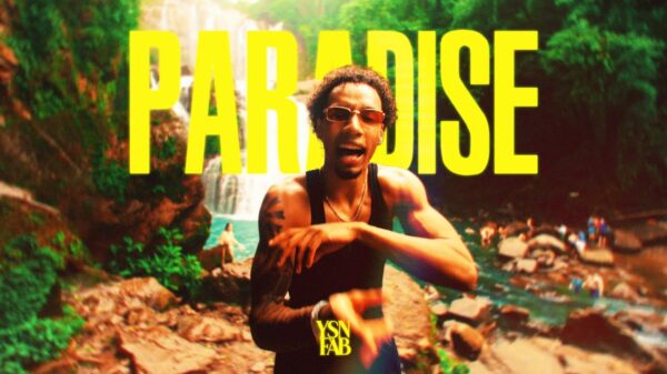 Rapper YSN Fab stands underneath the word PARADISE which is written in all caps and yellow.
