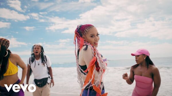 Sho Madjozi stands on a beach in the music video for Chalé