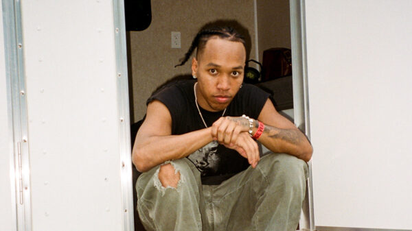 Canadian rapper Boslen sits on steps with his hands folded.