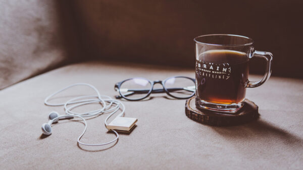 Headphones laying next to eye glasses and a glass of Turkish coffee.