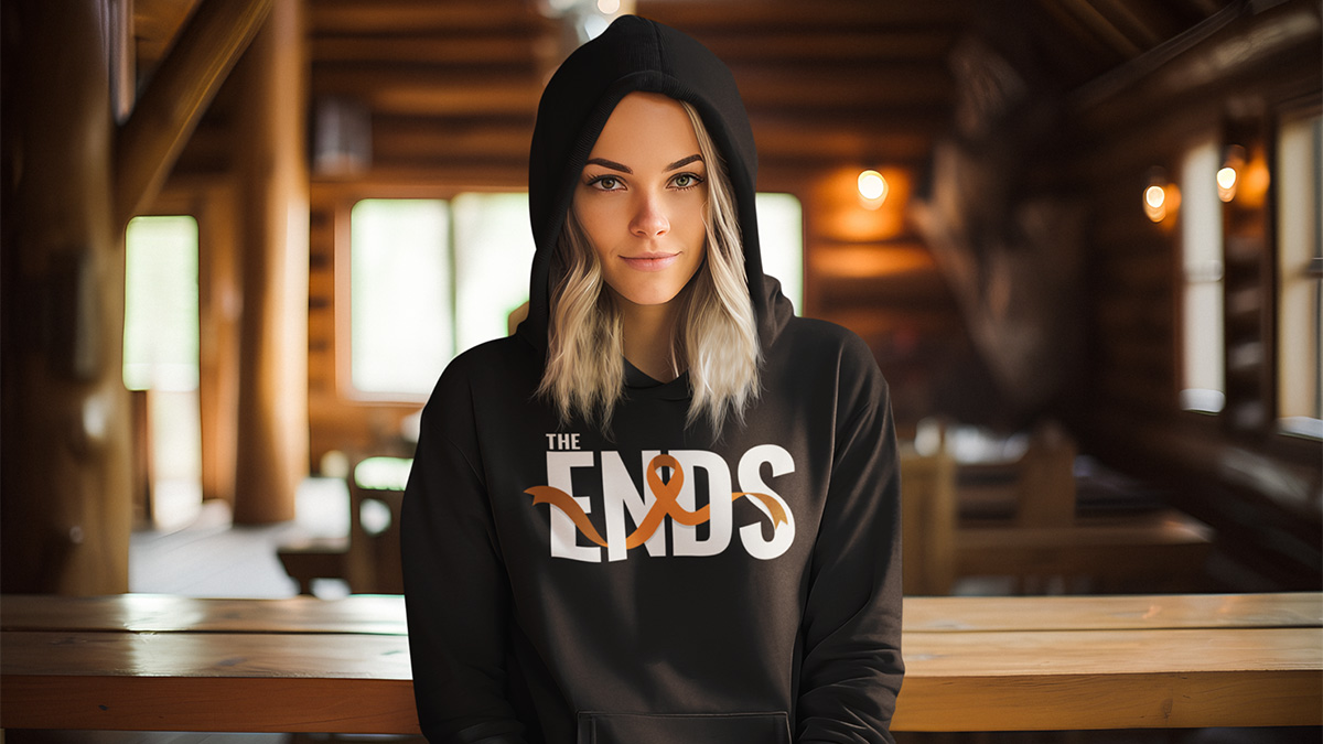 A young woman poses for a photo will wearing a black hoodie from The Ends Fight Ribbon collection.