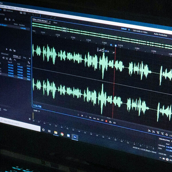 A laptop with audio editing software on the screen.