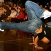 A breakdancing event with a breakdancer in the middle of a circle of people.