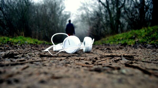 A person walking away from headphones left on the ground, an example of music anhedonia.