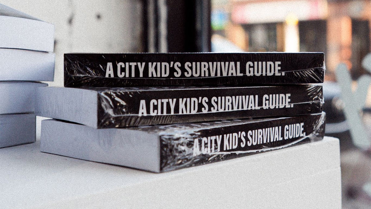 Three copies of 100: A City Kid's Survival Guide stacked on a table.