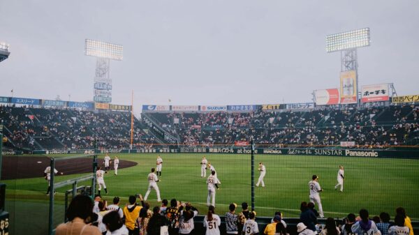 Fans watching players warm up on the field at a Japanese baseball stadium, capturing the atmosphere and excitement surrounding the MLB Japan Series.