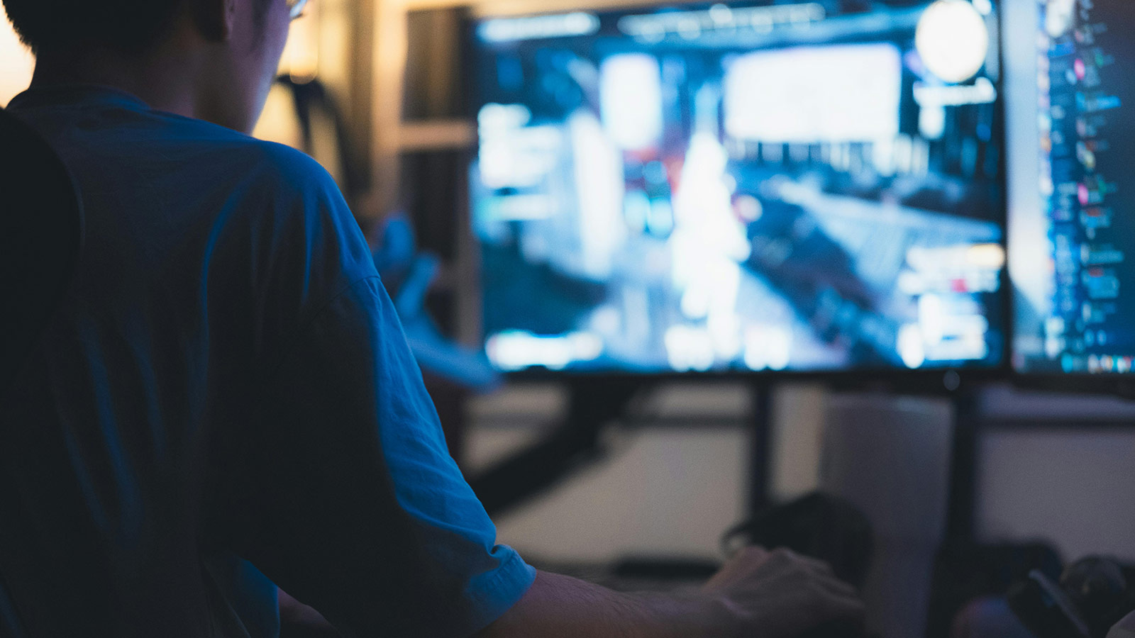 Person playing a video game in front of multiple screens, illustrating the impact of the US$55B Electronic Arts takeover 2025 on the gaming industry and workers.