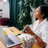 A woman sits at her desk recording a video with a product in her hand, highlighting the growing trust in influencers.